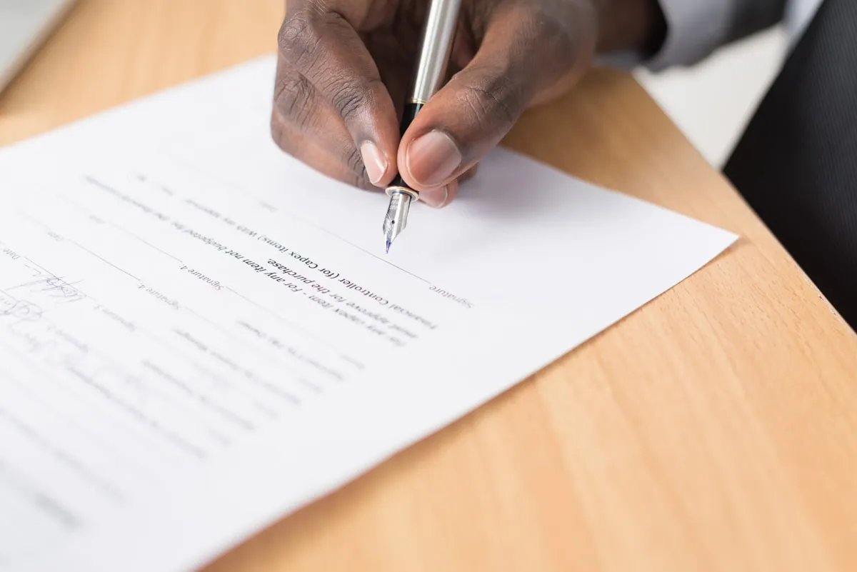 Professional signing a document at a meeting table
